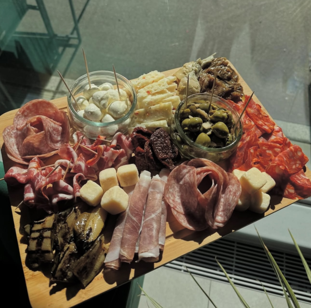 Tagliere mit Salumi und Antipasti im Sonnenlicht